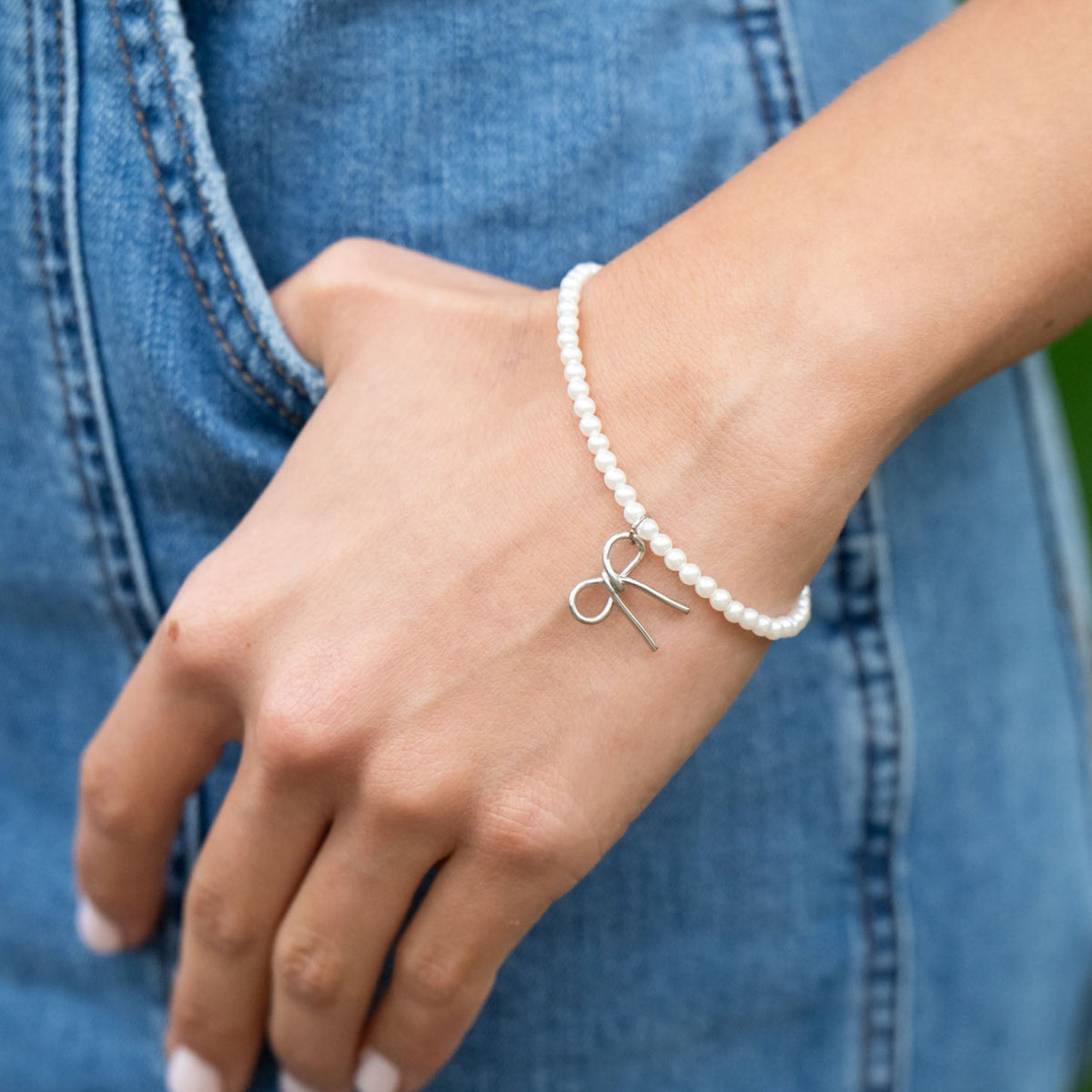 Delicate and timeless, the Pearls &amp; Bow Bracelet features a hand-shaped brass bow paired with dainty faux pearls, creating a piece that adds elegance and charm to any look. The bow symbolizes resilience and the strength of lives beautifully tied together.

Handcrafted by a young woman escaping human trafficking in India, each bracelet carries a story of hope, dignity, and new beginnings. Your purchase supports her journey through our non-profit, International Sanctuary.
