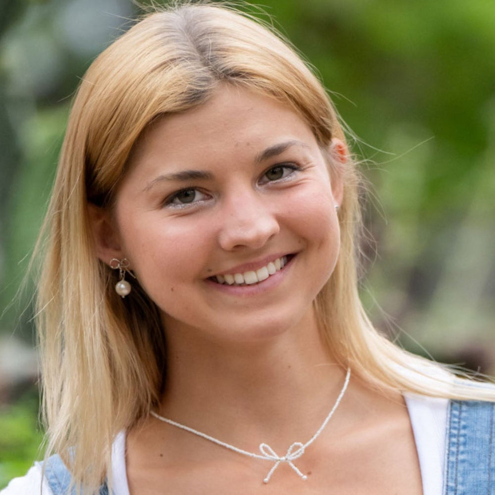 Delicate and timeless, our hand-forged Pearl Bow Studs are perfect for everyday wear. Each stud features a handcrafted brass bow paired with a luminous pearl, securely finished with sterling silver posts.

Every detail—from cutting and hammering to final assembly—is carefully done by a young woman in India rebuilding her life after human trafficking. With each purchase, you support her journey toward hope, dignity, and a brighter future through our non-profit, International Sanctuary.