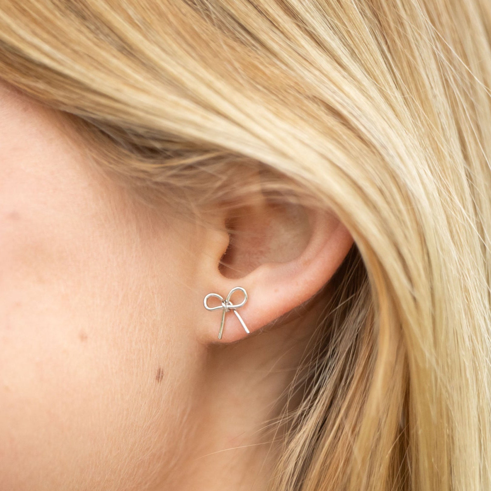 handmade bow studs brass gold Simple yet meaningful, these dainty hand-forged bows are perfect for everyday wear. Symbolizing resilience and strength, the bow serves as a reminder of lives beautifully tied together through hope and freedom. Each stud is carefully shaped by hand and finished with sterling silver posts for comfort and durability.

Hand-cut, hammered, and assembled by a young woman in India rebuilding her life after human trafficking, every pair carries her story of courage and dignity. Your p