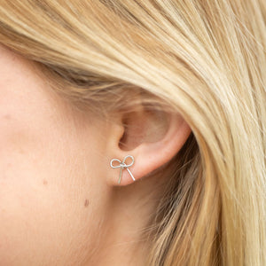 Simple yet meaningful, these dainty hand-forged bows are perfect for everyday wear. Symbolizing resilience and strength, the bow serves as a reminder of lives beautifully tied together through hope and freedom. Each stud is carefully shaped by hand and finished with sterling silver posts for comfort and durability.

Hand-cut, hammered, and assembled by a young woman in India rebuilding her life after human trafficking, every pair carries her story of courage and dignity. Your purchase supports her journey t