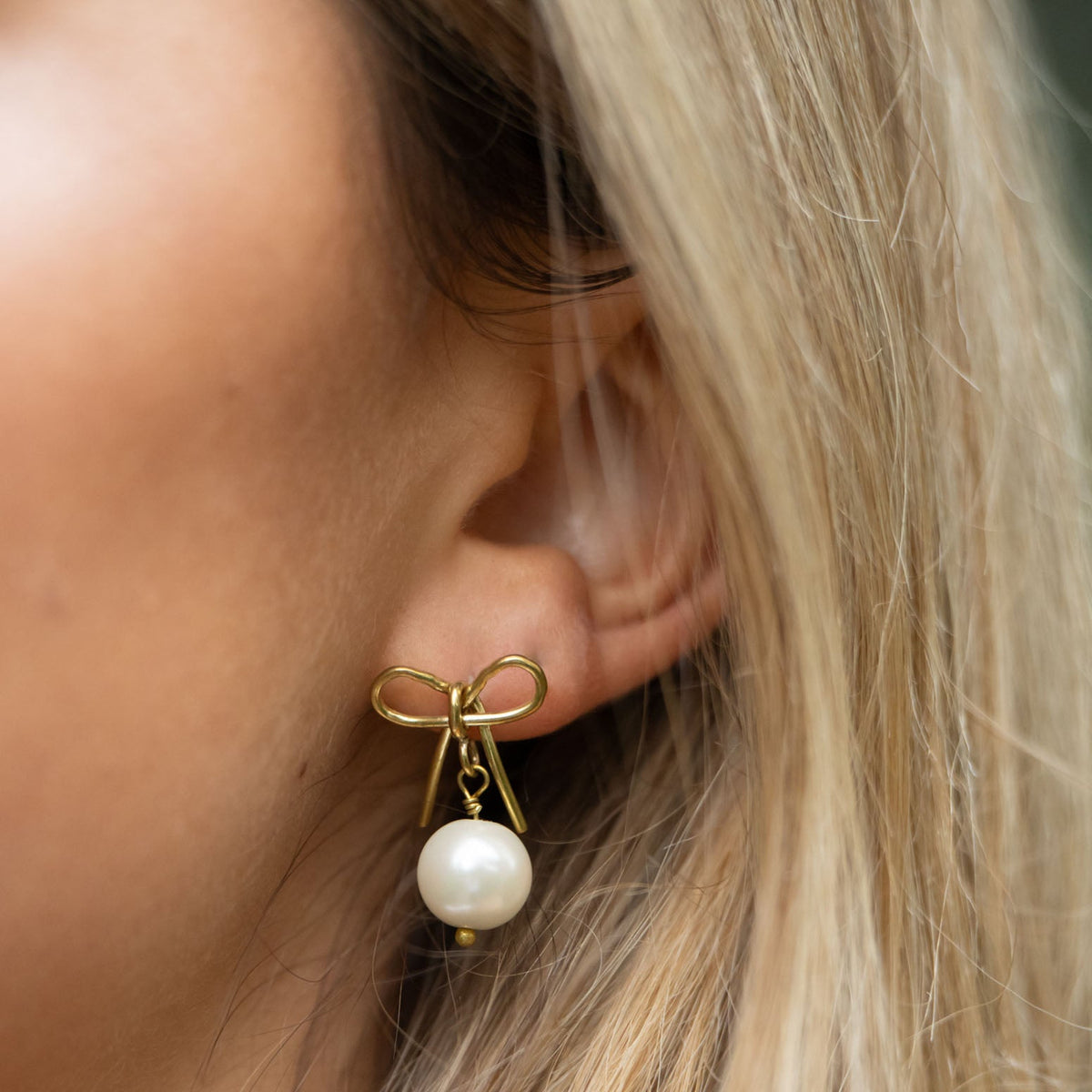 Delicate and timeless, our hand-forged Pearl Bow Studs are perfect for everyday wear. Each stud features a handcrafted brass bow paired with a luminous pearl, securely finished with sterling silver posts.

Every detail—from cutting and hammering to final assembly—is carefully done by a young woman in India rebuilding her life after human trafficking. With each purchase, you support her journey toward hope, dignity, and a brighter future through our non-profit, International Sanctuary.