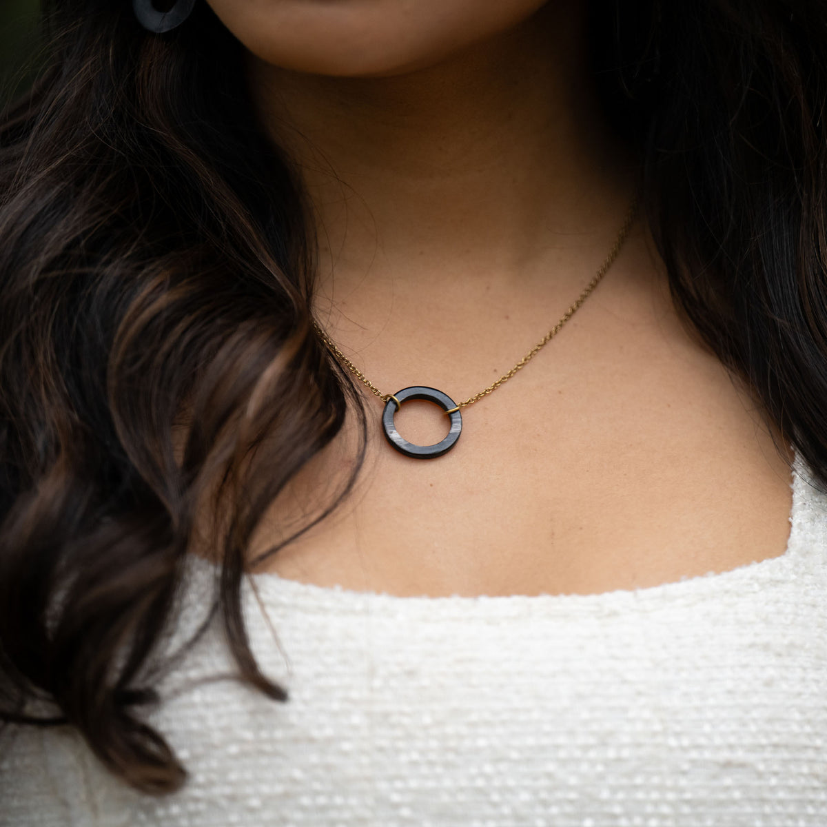 Our best-selling Unity Necklace now comes in ankole, a natural material with stunning variations in color ranging from deep ivory-black to warm caramel and creamy white. Each polished piece is truly one-of-a-kind—just like a fingerprint.

The necklace features a simple, textured circle pendant on an 18&quot; chain with a 2&quot; extender, making it perfect for layering or wearing on its own. For a complete set, pair it with the Unity Ankole Bracelet.

Handcrafted in Uganda, this necklace is more than jewelry